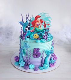 the little mermaid cake is decorated with blue and purple icing