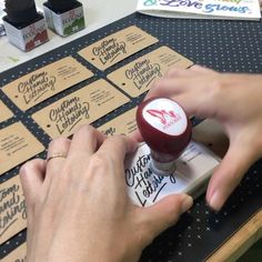 a person is stamping out some business cards on a table with other items in the background