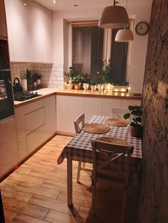 a table and chairs in a small kitchen with lights on the window sill above it