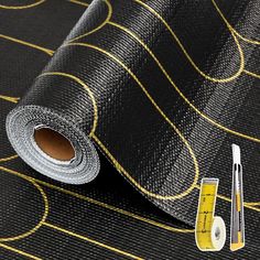 a roll of black and gold wallpaper next to a measuring tape