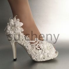 a woman's white high heeled shoe with flowers on the side and lace detailing