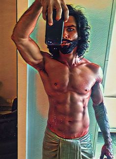 a shirtless man taking a selfie in the mirror with his cell phone,