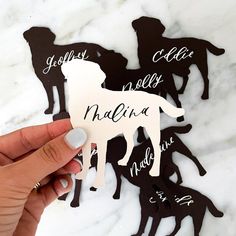 a person holding up a cut out of paper with the silhouettes of dogs on it