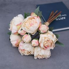 a bouquet of flowers sitting next to an open book