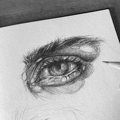 a pencil drawing of an eye on paper with a pen in front of the eye