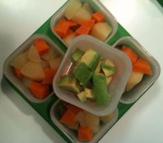 four plastic containers filled with different types of fruit and veggies on top of a table