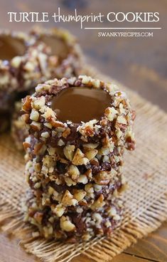 chocolate turtle thumbprint cookies are stacked on top of each other with chopped walnuts