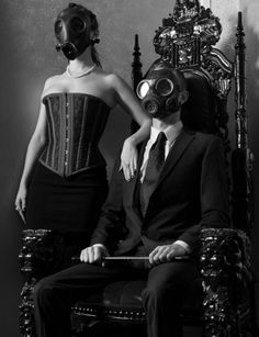 a man in a gas mask sitting next to a woman wearing a dress on a chair