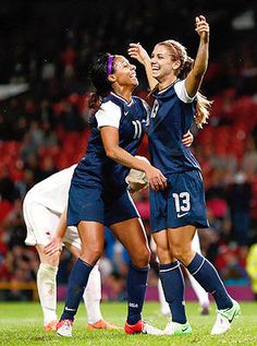 two female soccer players are celebrating on the field