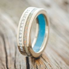 a wedding ring with white gold and blue enamel inlays on top of a piece of wood