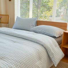 a bed with blue and white checkered comforter in a bedroom next to a window