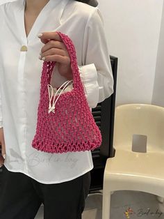 a woman holding a pink crocheted bag in her hands and wearing black pants