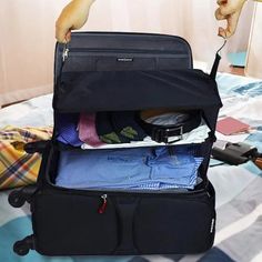 a person holding an open suitcase with clothes in it