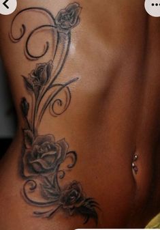 a woman's stomach with flowers on it and an arrow in the back tattoo