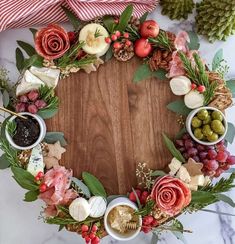 a christmas wreath made out of cheese, meats and vegetables on a wooden board