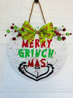 a merry grinmas sign hanging on a door with green and red paint splatters