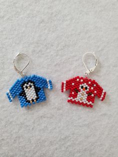 two small beaded penguin keychains sitting on top of white snow covered ground