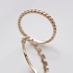 two gold rings with small beads on each side, one in the shape of a circle