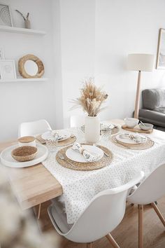 a dining room table set for four with place settings and plates on it, in front of a couch