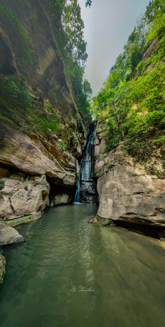 there is a small waterfall in the middle of some rocks and green trees around it