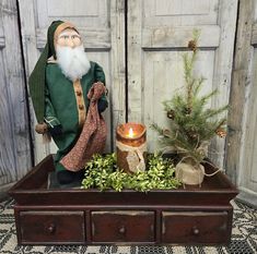 a wooden table topped with a figurine next to a candle and potted plant