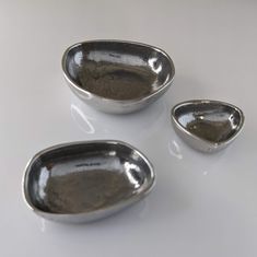 three silver bowls sitting on top of a white table