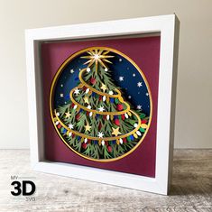 a paper cut christmas tree in a white frame on a wooden table with the words 3d over it