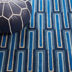 a blue and white rug with a round poufce on it next to a black ottoman