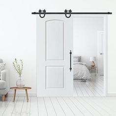 an open door leading to a bedroom with white walls and wood flooring is shown