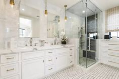 a white bathroom with two sinks and a walk in shower