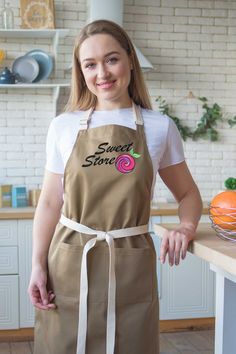 a woman standing in a kitchen wearing an apron with the words sweet store on it