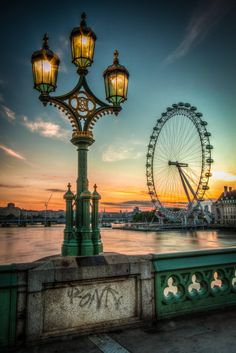 the ferris wheel is lit up at sunset