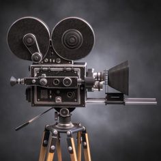 an old fashioned camera sitting on top of a tripod in front of a purple background