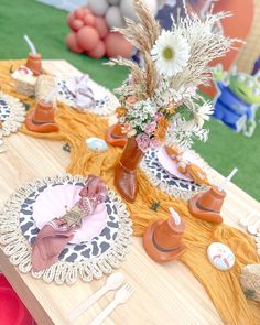 the table is set with plates, cups and flowers in vases on top of doily