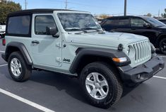 a light green jeep parked in a parking lot