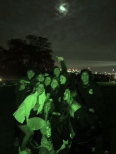 a group of people standing next to each other in front of the moon at night