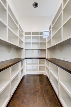 an empty walk in closet with white shelving and wood flooring, along with hard wood floors