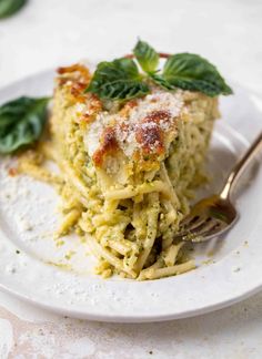 a white plate topped with lasagna covered in pesto and parmesan cheese