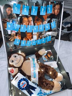 a teddy bear in a suitcase with pictures on the side and blue ribbon around it