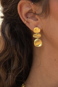 -18k gold plated earrings with molten brushed gold coins. -Measures 1" -Handmade in Brazil -18k gold plated over brass Unique Jewelry Gold, Gold Seventies Inspired Jewelry, Funky Jewelry Gold, Funky Gold Earrings, Cool Gold Earrings, Unique Jewelry Inspiration, Textured Jewellery, Dangly Gold Earrings, Unique Earrings Gold