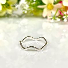 a silver ring sitting on top of a table next to flowers