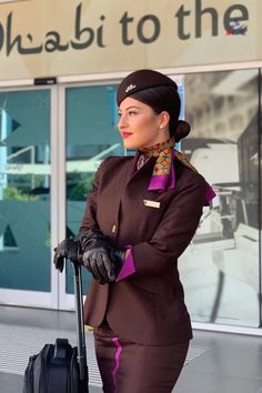 a woman in an airline uniform holding a suitcase