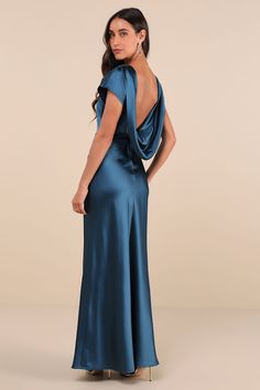 the back of a woman wearing a long blue dress with an open neck and draped shoulders