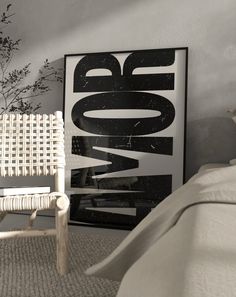 a white chair sitting next to a bed in a bedroom under a poster on the wall