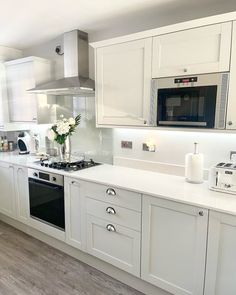 a kitchen with white cupboards and appliances in it's center island, next to a stove top oven