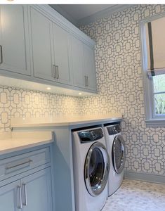 a washer and dryer in a room with blue cabinets on either side of the window