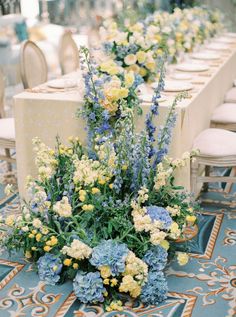 the table is set with blue and yellow flowers