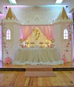 a table with cake on it in front of a white brick wall and pink drapes