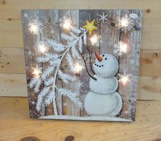 a snowman holding a star on top of a wooden board with lights around it