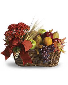 a basket filled with fruit and vegetables on top of a white background, next to a red bow